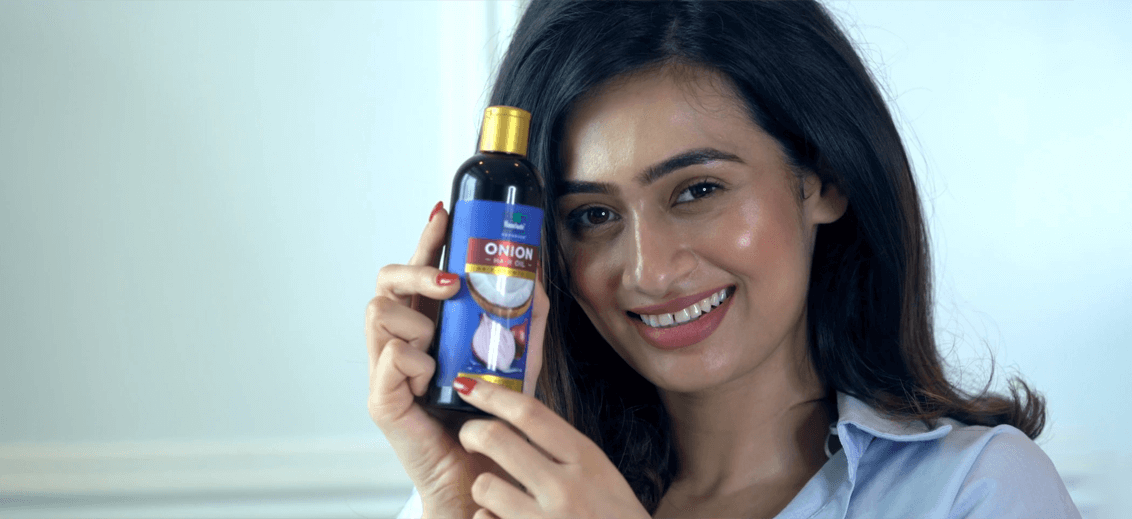 A smiling woman with gorgeous long hair after using Parachute Advansed Hot Oil 